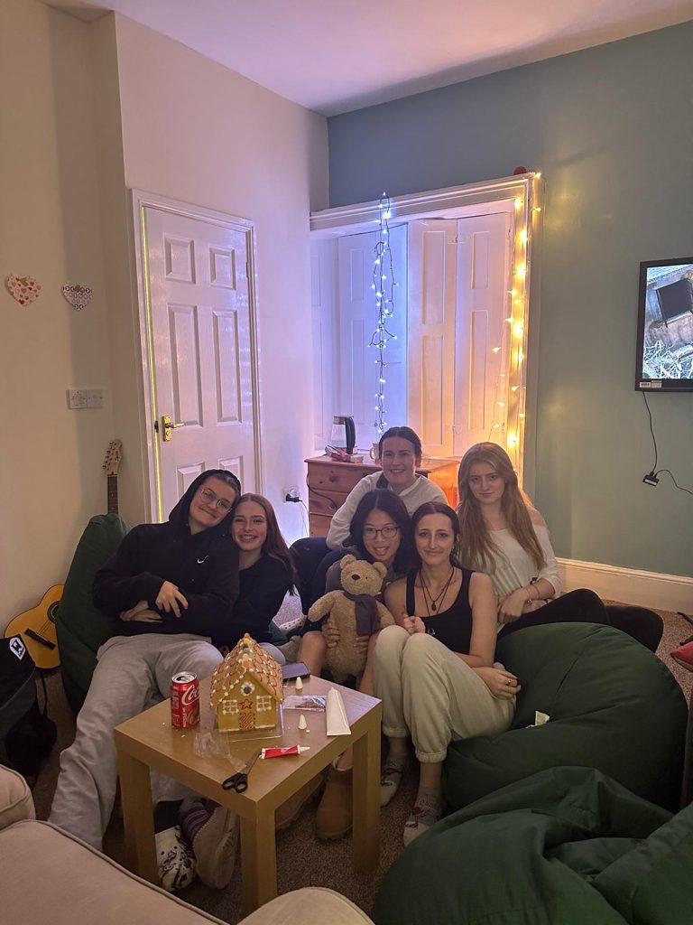 A group of six female Langley boarders sitting together in Langley boarding house ready to watch a film